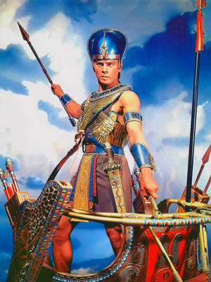 埃及戰士身穿金色盔甲，在戰車上手持長矛，背景為多雲天空
