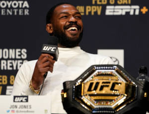 Jon Jones 在記者會上手持UFC冠軍腰帶微笑。