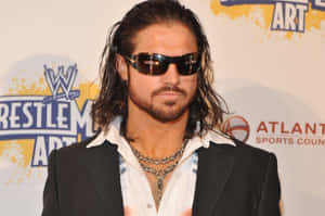 WWE摔角手留著長髮、戴著太陽眼鏡，在活動中身穿西裝和鏈條。