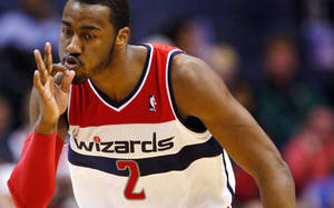 穿著巫師隊球衣的職業籃球運動員在比賽中做出手勢。