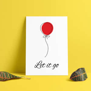 一個白色印刷品，上面有一個紅色氣球和「Let it go」短語，靠在一面有葉子的黃色牆上。 — 黃色美學 壁紙