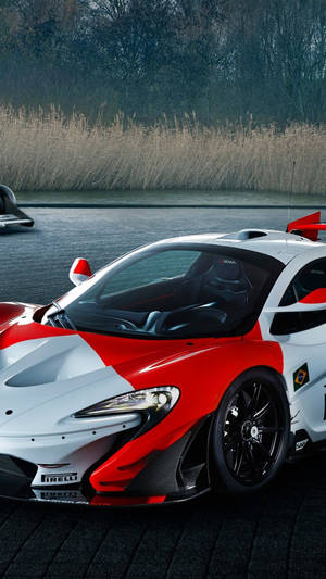 紅白相間的McLaren Senna賽車停泊在近水處，有蘆葦。