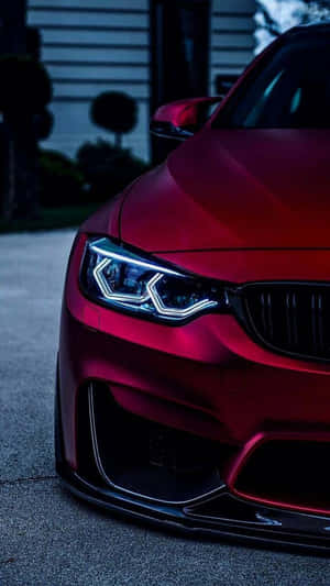 光澤紅色BMW跑車在黃昏時停車，車頭燈亮起。