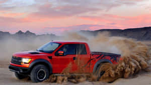 紅色福特F-150 Raptor貨車在沙漠中行駛，日落時揚起塵土。 — 汽車 壁紙
