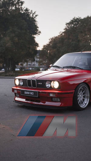 黃昏時分停泊的紅色BMW M3跑車，行人路上發光的M標誌。