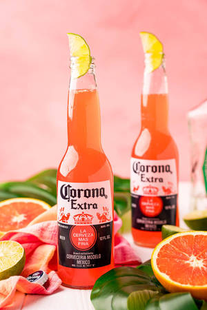 兩瓶Corona Extra啤酒配上青檸裝飾，周圍環繞著柑橘和熱帶葉子。 — 檸檬 壁紙