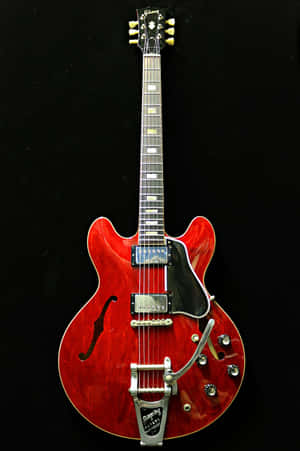 黑色背景上，一把帶有銀色硬件的紅色 Gibson 電結他。