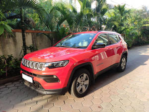 紅色Jeep Compass SUV停泊在六角形瓷磚車道上，配有棕櫚樹 — 汽車 壁紙