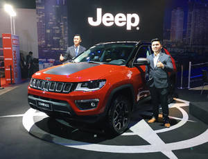兩名穿西裝的男子在車展上於一輛紅色Jeep Compass旁邊豎起大拇指。 — 汽車 壁紙
