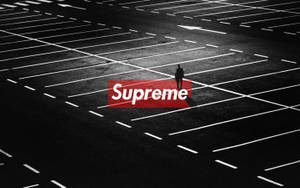一個孤獨的人站在空曠的停車場，帶有紅色Supreme標誌。