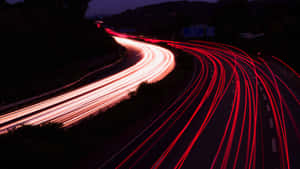 夜間彎曲的高速公路上有紅色和白色汽車燈光的條紋。