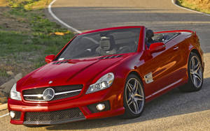 紅色Mercedes-Benz SLR McLaren開篷車停泊在日落時分的彎曲道路上。