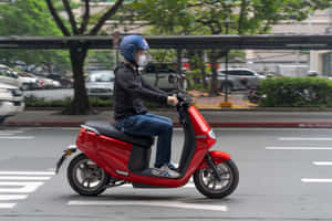 喺城市街道上騎紅色滑板車嘅人，背景有樹木同汽車。