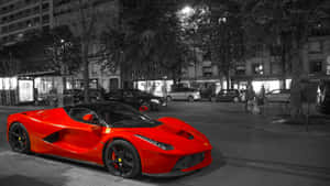 一輛紅色法拉利LaFerrari停在夜晚的城市街道上，有行人經過。
