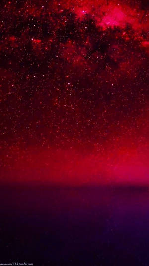 在黑暗地平線之上，帶有宇宙雲的鮮豔紅色和紫色星空。