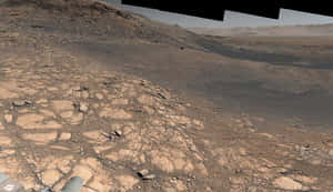 探測車在塵土飛揚的天空下探索裂開的岩石火星表面。