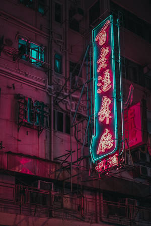 霓虹燈在夜間用粉紅色和藍綠色的色調照亮密集的城市建築。