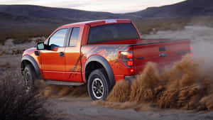 橙色福特 F-150 Raptor 卡車在日落時分的沙漠中揚起塵土。