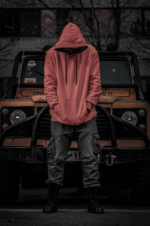 穿紅色連帽衫的人低頭站在橙色卡車前。 — 汽車 壁紙