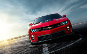 紅色雪佛蘭Camaro ZL1在日落時分的賽道上比賽。