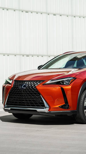 橙色Lexus SUV在白天停靠在白色波紋板牆旁。