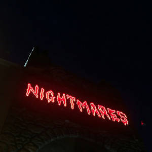 夜間石拱門上寫有 nightmares 的紅色霓虹燈牌。