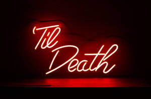 深色牆上以草書顯示「Til Death」的紅色霓虹燈牌。 — 霓虹美學 壁紙