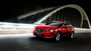 紅色Mazda6旅行車在夜間於燈光拱橋下疾馳。