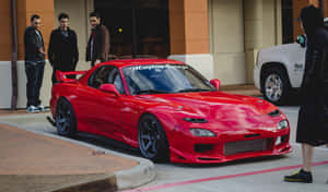 紅色萬事得RX-7跑車配備定制車身套件，停泊在城市街道上，有男子欣賞。