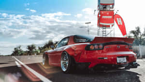 日落時分賽道上的紅色萬事得RX-7跑車。