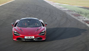 紅色McLaren 720S在賽道上飛馳，帶有輪胎痕跡和路緣。 — 4K 法拉利 壁紙