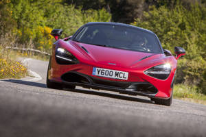 紅色McLaren 720S在風景如畫的鄉村道路上飛馳，周圍綠樹和野花環繞。 — 4K 法拉利 壁紙