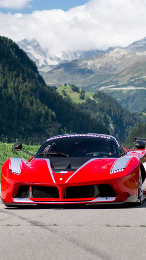 紅色法拉利 LaFerrari 停泊在山路上，背景有白雪覆蓋的山峰和翠綠的森林。 — 汽車 壁紙