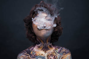 身體彩繪的人在黑暗背景下呼出煙霧