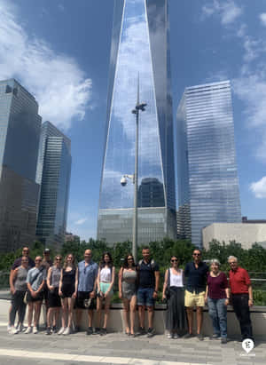 一群遊客在陽光明媚的日子裡在One World Trade Center前擺姿勢。 — 藍天 壁紙