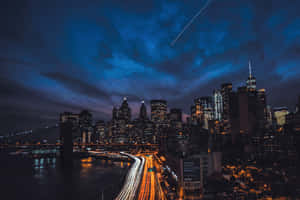 夜間紐約天際線，發光的建築物和交通燈光軌跡。 — 夜空 壁紙