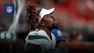 身穿白色和綠色球衣的NFL美式足球員在比賽中向上看。