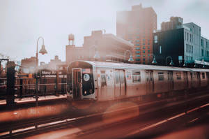Marcy Avenue 車站的銀色地鐵列車，金色夕陽餘暉和背景建築。