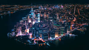 紐約市天際線的夜間空中景觀，有發光的摩天大樓和水面倒影。 — 紐約市 壁紙