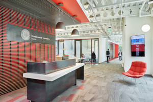 Northeastern University Seattle 大堂，設有紅色牆壁、接待處和橙色椅子。