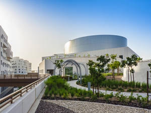 日落時分，現代白色曲線建築，設有屋頂花園和小徑。