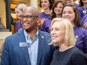 參議員 Emanuel Jones 在室內政治活動中與一位女性微笑。 — 微笑 壁紙