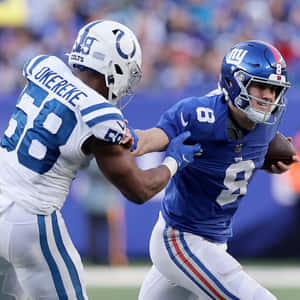 身穿藍色球衣的橄欖球運動員帶球奔跑，同時被對手擒抱。 — NFL 美式足球 GIF 壁紙
