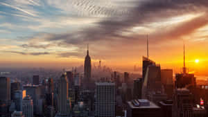 紐約天際線在夕陽下，金色光芒和戲劇性的雲彩。 — 紐約市 壁紙