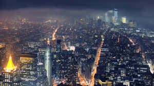 密集城市天際線的夜間鳥瞰圖，建築物和街道閃閃發光。