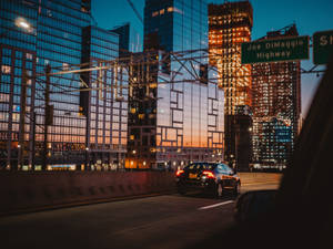 黃昏時分高速公路上的汽車，背景是燈火通明的摩天大樓