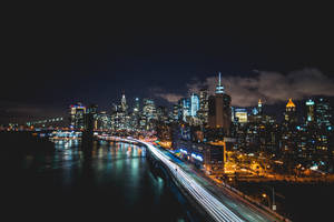 紐約天際線的夜景，建築物燈火通明，汽車留下光軌。