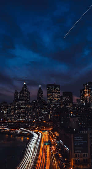 夜晚的城市天際線，發光的建築物和移動汽車的光軌，在黑暗的天空中有一顆流星。 — 夜景城市 壁紙
