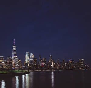 夜景城市景觀，閃爍的摩天大樓倒映在水中。