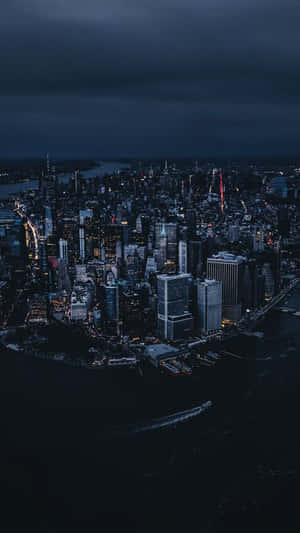 夜晚城市的鳥瞰圖，有明亮的摩天大樓和暴風雲下的黑暗水面。 — 夜景城市 壁紙